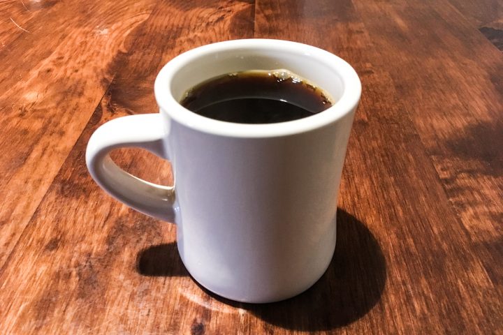 White-Mug-of-Coffee-on-Wood-Table